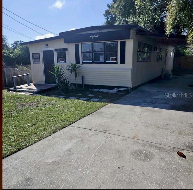 A single-story house with light-colored siding, a concrete driveway, and a small front deck — 5609 LEISURE LANE, NEW PORT RICHEY, FL