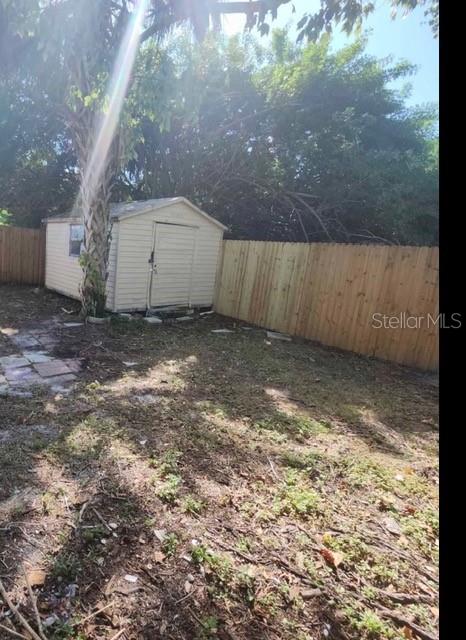 A small storage shed sits in a backyard enclosed by a wooden privacy fence — 5609 LEISURE LANE, NEW PORT RICHEY, FL