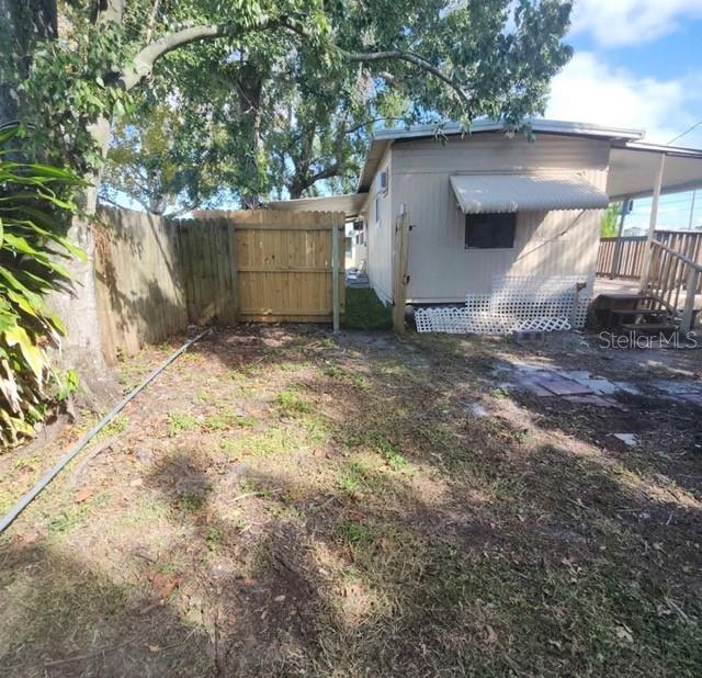 A side view of a mobile home with a wooden fence and a small yard — 5609 LEISURE LANE, NEW PORT RICHEY, FL