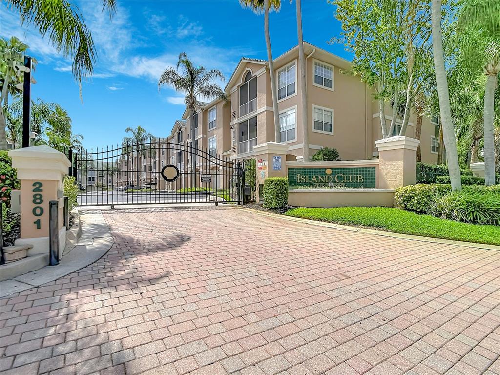 A gated entrance leads to a multi-story apartment building with a brick-paved driveway — 5308 BAY CLUB CIRCLE UNIT 5308, TAMPA, FL