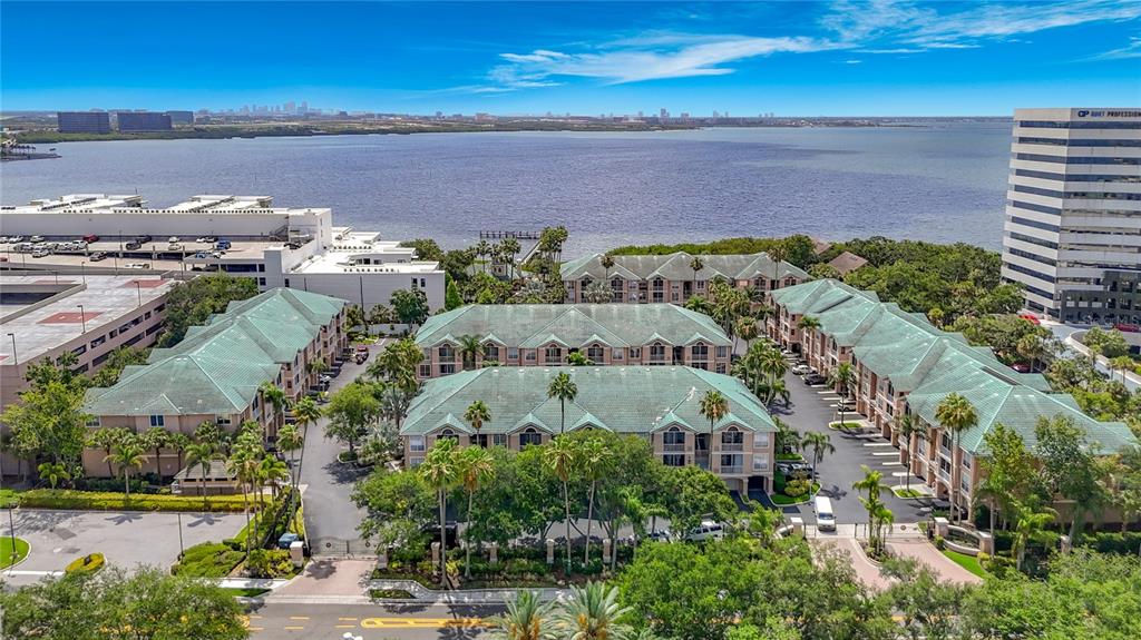 An aerial view shows a multi-story apartment complex with green roofs near a large body — 5308 BAY CLUB CIRCLE UNIT 5308, TAMPA, FL