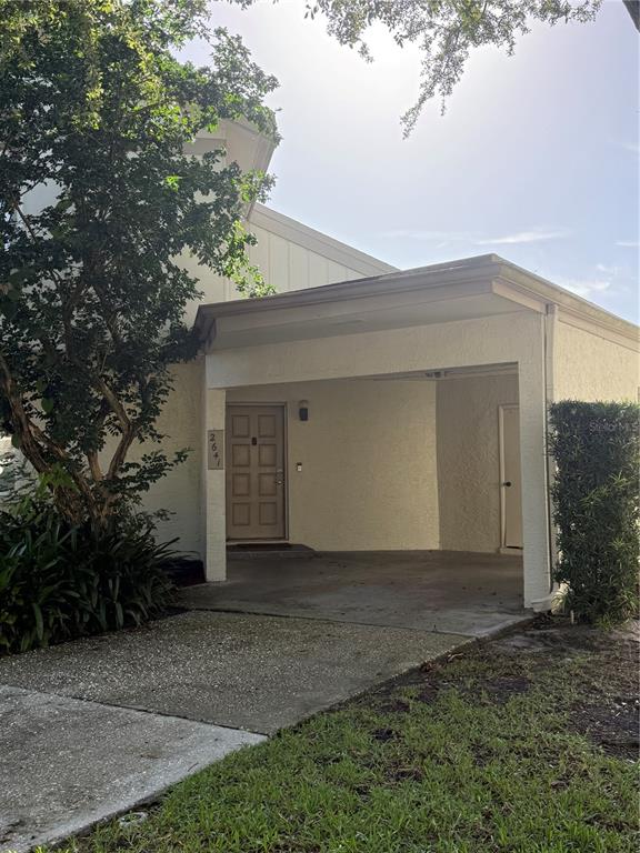 A beige house exterior features a covered carport, a front door, and a large tree — 2641 CEDAR VIEW COURT, CLEARWATER, FL