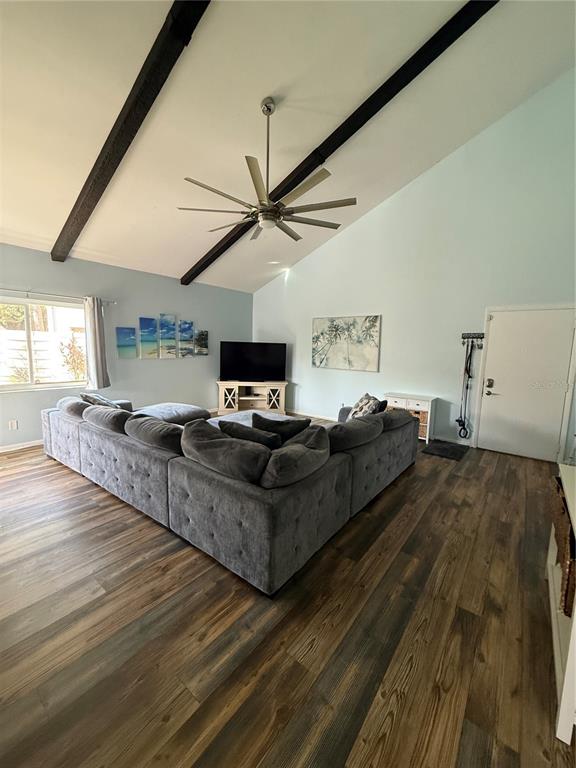 A living room features a large gray sectional sofa, vaulted ceilings with exposed beams, and wood-look flooring — 2641 CEDAR VIEW COURT, CLEARWATER, FL