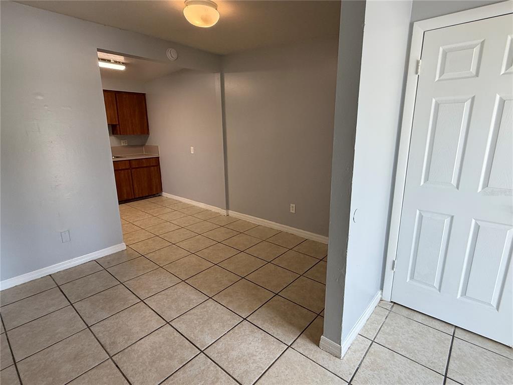 A tiled room with light gray walls leads to a kitchen with wood cabinets — 2602 TRINITY CIRCLE NW UNIT B, WINTER HAVEN, FL