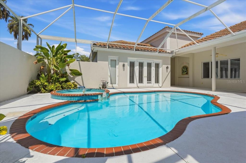 A screened-in patio features a swimming pool, a raised hot tub, and a tropical plant — 5221 88TH STREET E, BRADENTON, FL