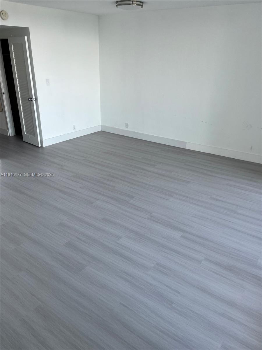 An empty room features white walls, light gray wood-look flooring, and a white closet door — 1000 West Ave # 1006, Miami Beach FL 33139, MIAMI BEACH, FL