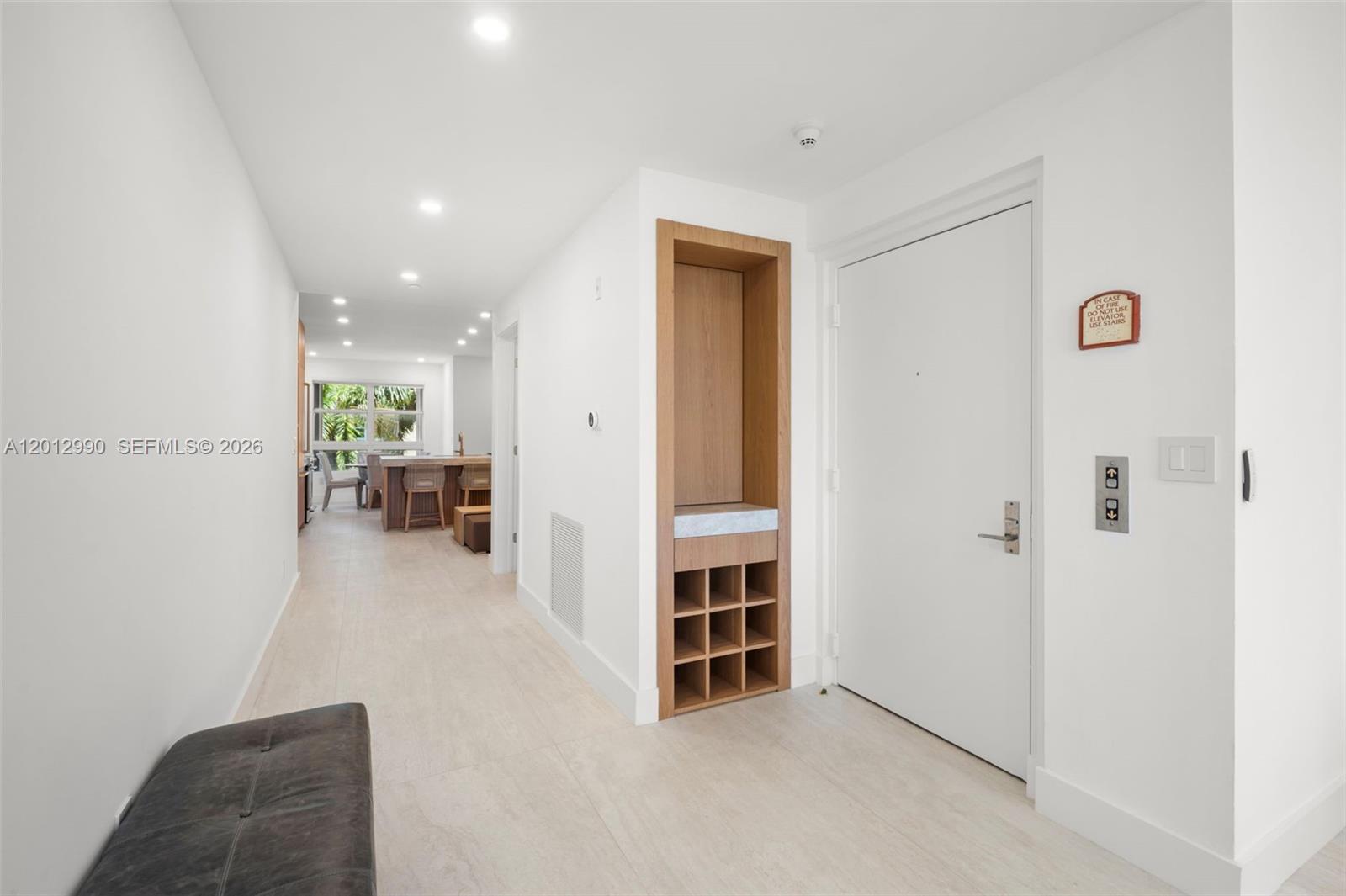An entryway features a white door, a built-in wooden cubby unit, and light tile flooring — 701 Crandon Blvd # 401, Key Biscayne FL 33149, KEY BISCAYNE, FL