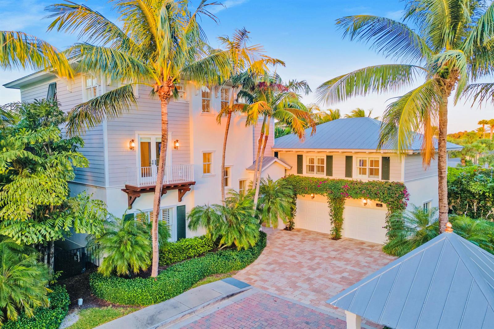 A two-story house with a paved driveway, palm trees, and a vine-covered garage exterior — 111 Beachwalk Lane, Jupiter FL 33477, JUPITER, FL