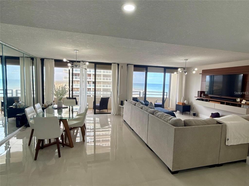 A modern living and dining area features tile floors, a sectional sofa, and ocean views — 2900 N ATLANTIC AVENUE UNIT 1503, DAYTONA BEACH, FL