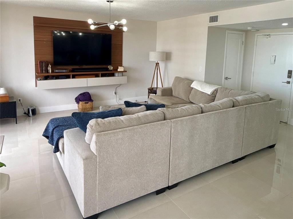A living room features a large sectional sofa, a wall-mounted television, and tile flooring — 2900 N ATLANTIC AVENUE UNIT 1503, DAYTONA BEACH, FL