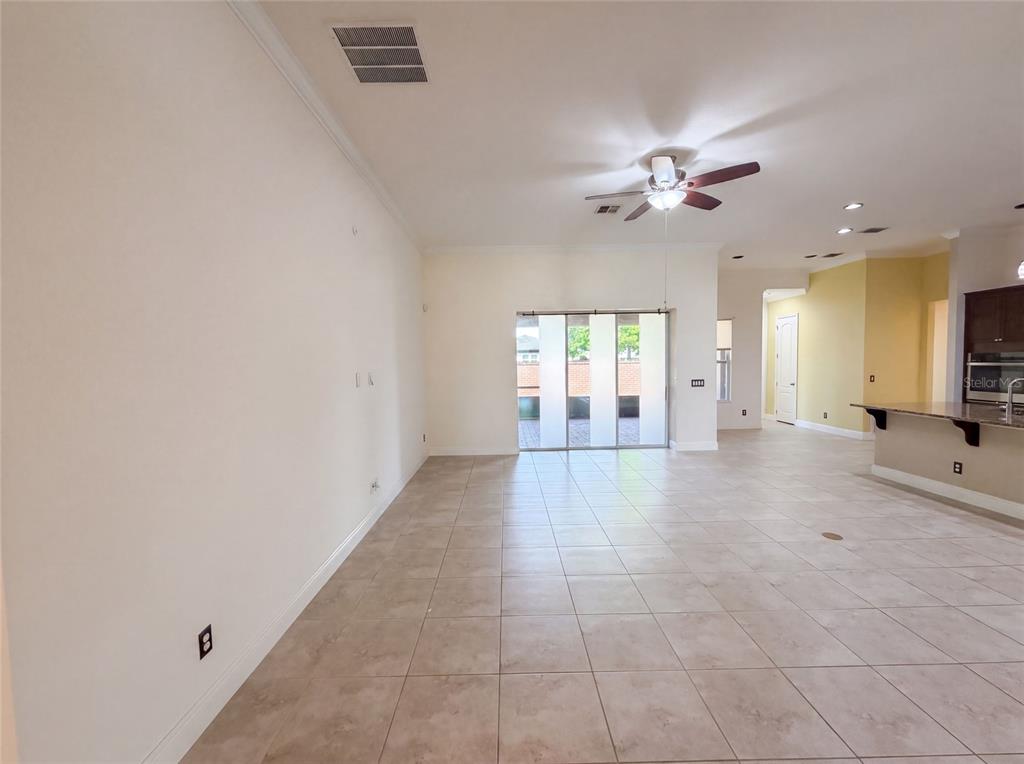 An open-concept living area features light-colored tile flooring, a ceiling fan, and sliding glass doors — 918 BLACKTHORN DRIVE, APOPKA, FL