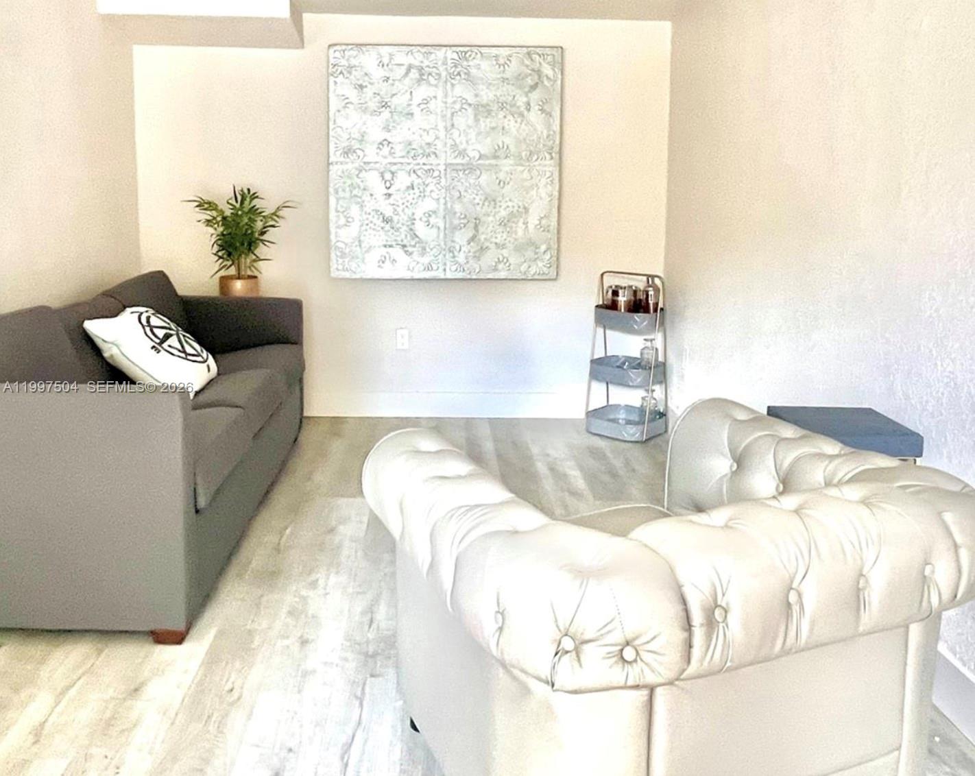 A living room features a gray sofa, a tufted white armchair, and wall art — 21 NE 53 ST, Miami FL 33137, MIAMI, FL