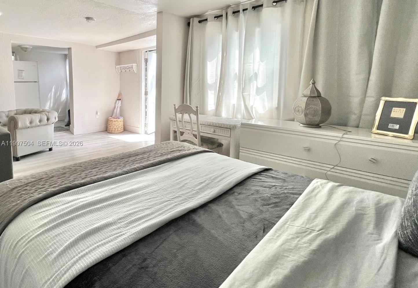 A bedroom features a bed, a white dresser, a desk, and a view into another room — 21 NE 53 ST, Miami FL 33137, MIAMI, FL