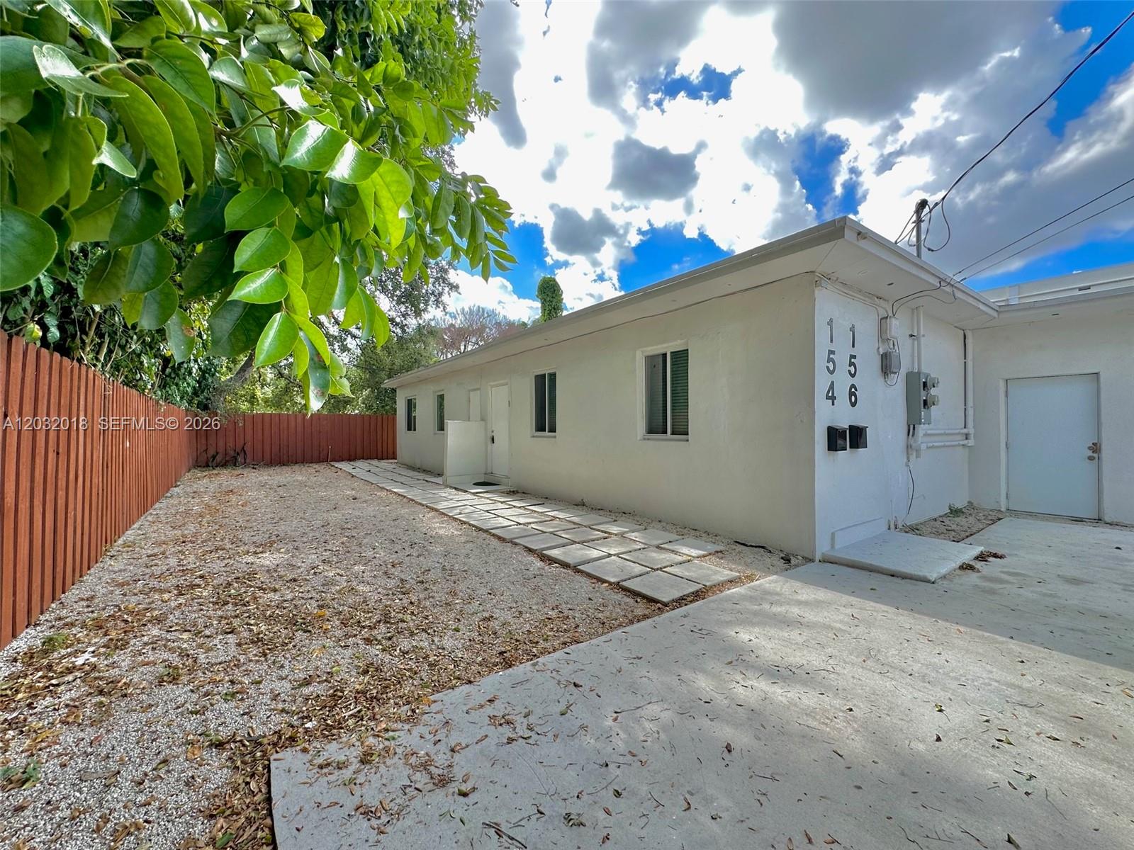 A white single-story building with a gravel yard and a concrete walkway — 156 NW 62nd St # 1, Miami FL 33150, MIAMI, FL