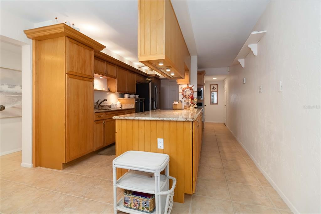 A kitchen features light wood cabinetry, a granite-topped island, and beige tile flooring — 4201 S ATLANTIC AVENUE UNIT 409, NEW SMYRNA BEACH, FL