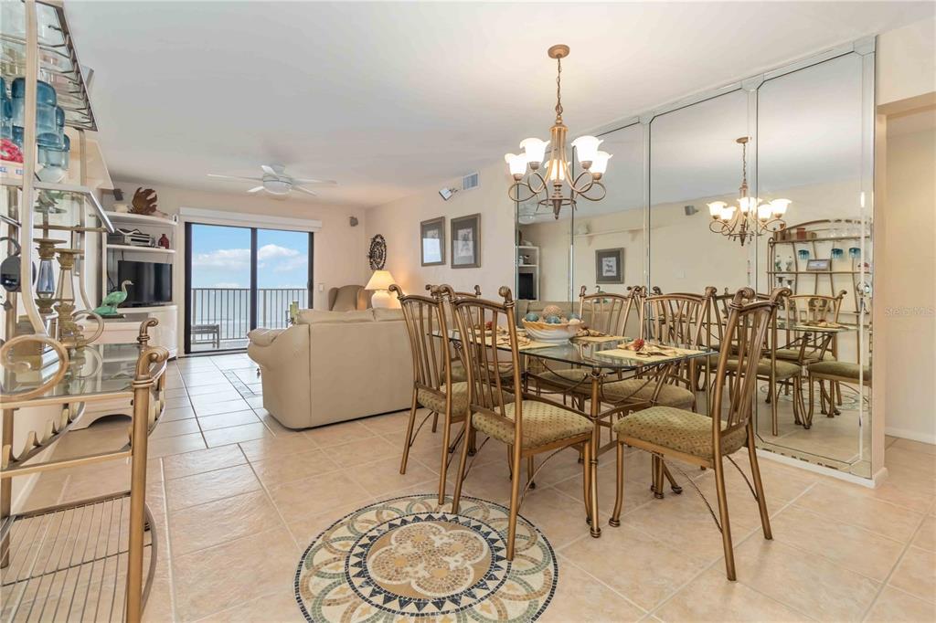 A dining area with a glass table and gold chairs sits before a mirrored wall — 4201 S ATLANTIC AVENUE UNIT 409, NEW SMYRNA BEACH, FL
