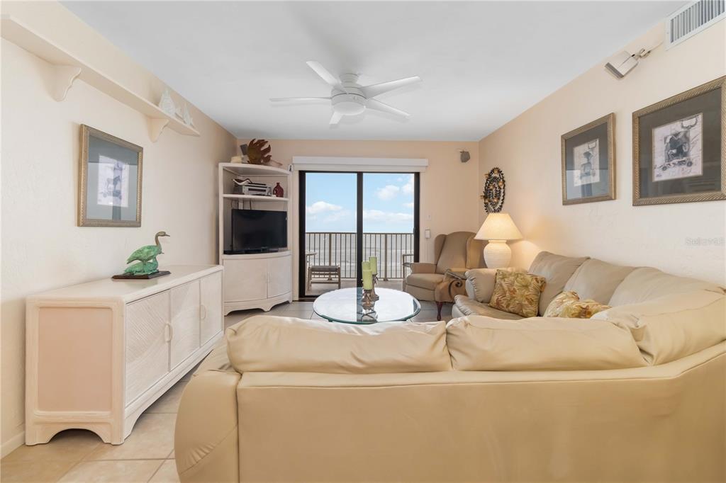 A living room features a beige sectional sofa, a white cabinet, and a sliding glass door — 4201 S ATLANTIC AVENUE UNIT 409, NEW SMYRNA BEACH, FL