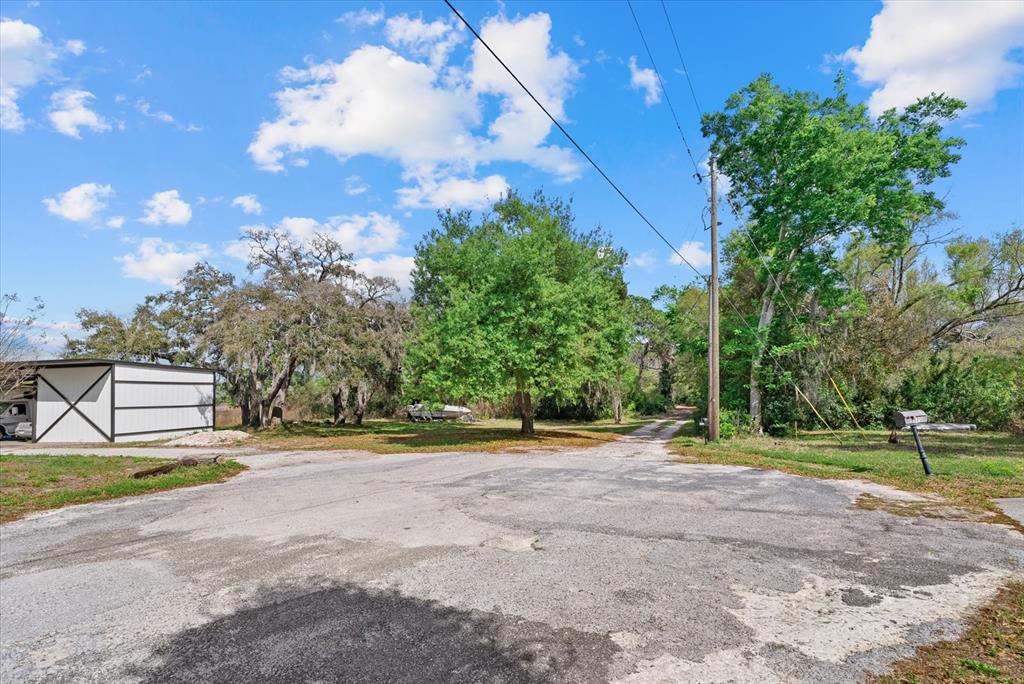 A paved road leads toward a white barn and trees under a blue sky — INDALE DRIVE, NEW PORT RICHEY, FL