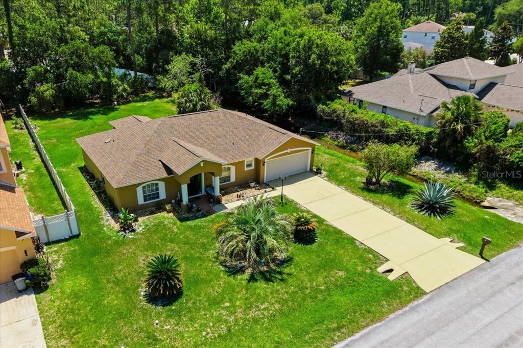An aerial view shows a single-story house with a brown roof, garage, and grassy yard — 34 BREWSTER LANE, PALM COAST, FL