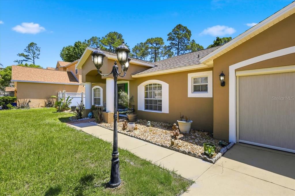 A tan house exterior features a front walkway, a decorative lamp post, and a garage — 34 BREWSTER LANE, PALM COAST, FL