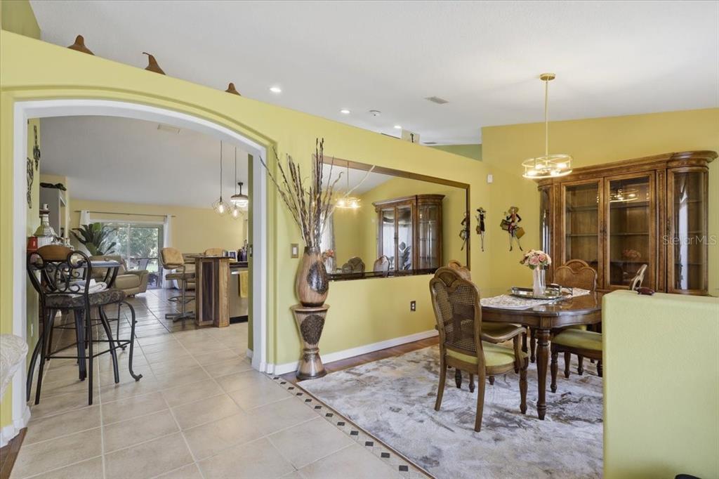 A dining room with a large mirror and hutch opens into a kitchen with bar seating — 34 BREWSTER LANE, PALM COAST, FL