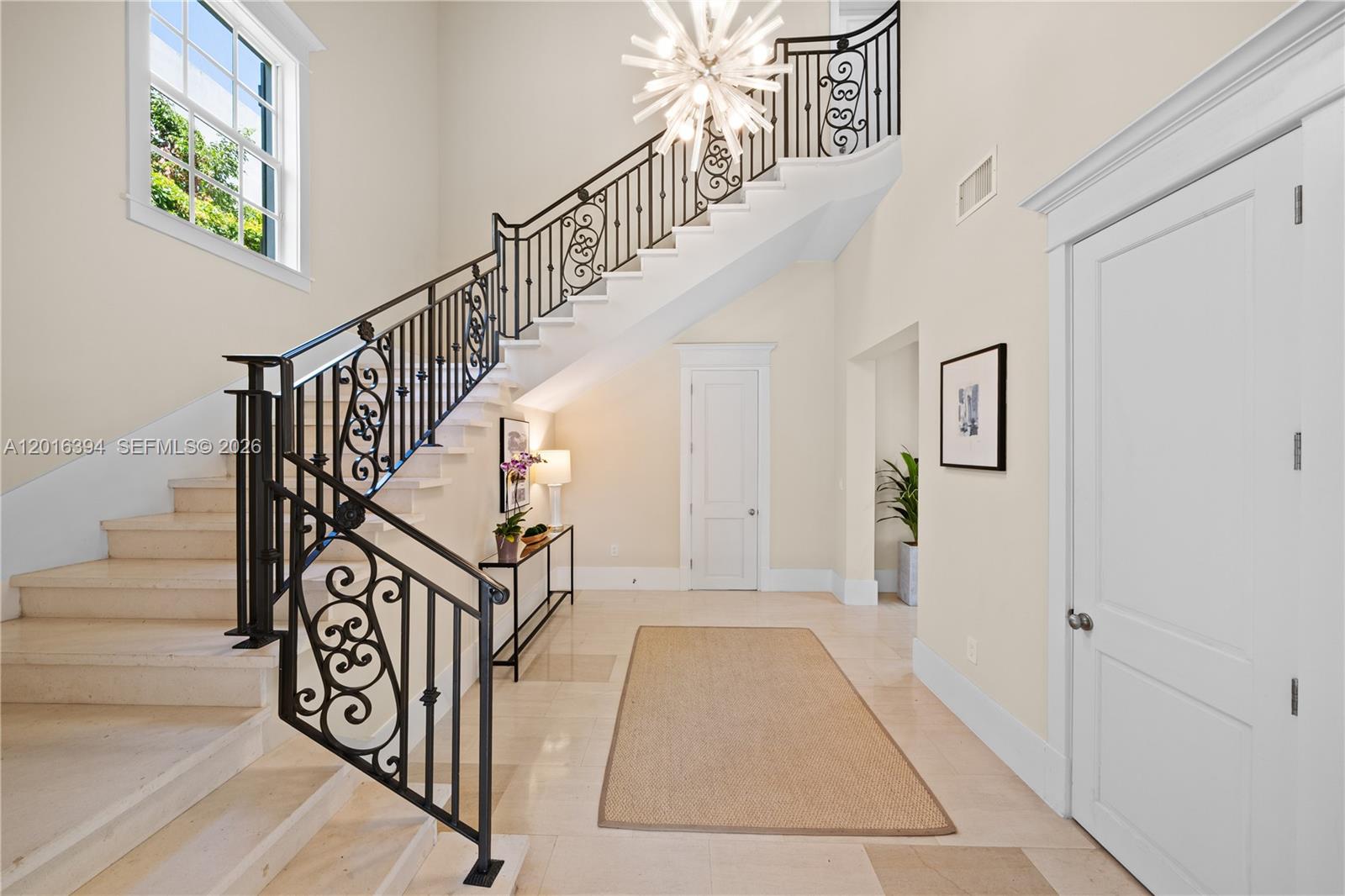 A grand foyer features a stone staircase with ornate iron railings and a chandelier — 7745 SW 54th Ave, Miami FL 33143, MIAMI, FL