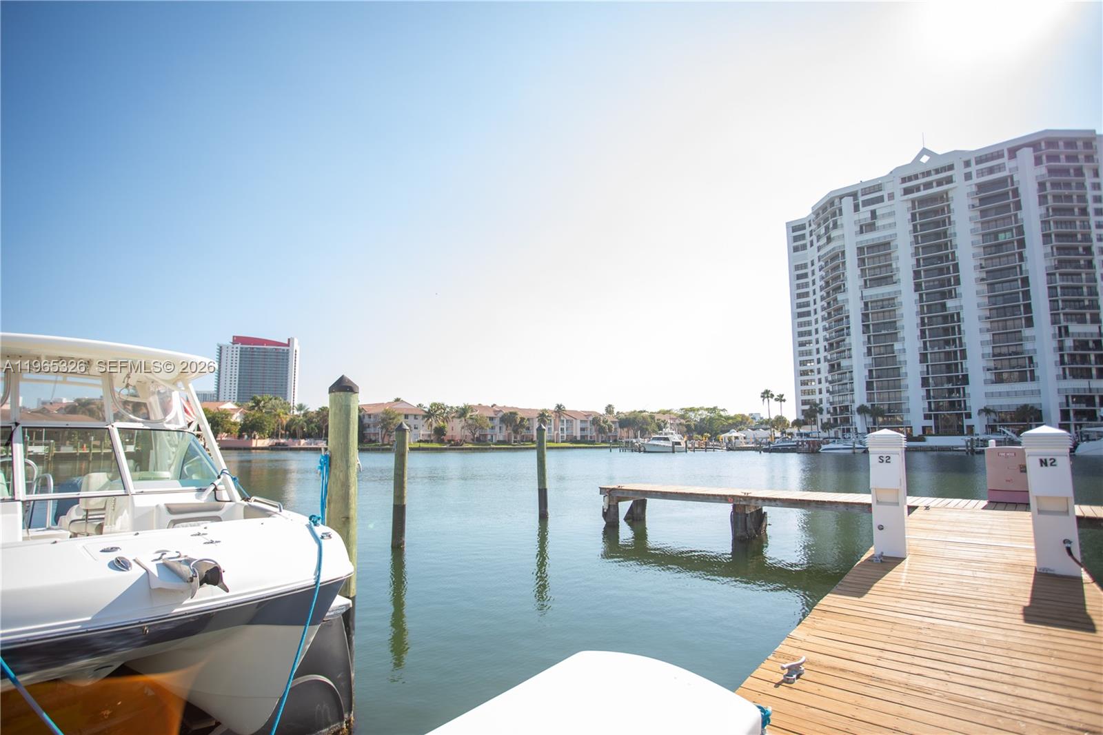 A white boat is docked at a wooden pier overlooking a canal and high-rise buildings — 523 Leslie Dr, Hallandale Beach FL 33009, HALLANDALE BEACH, FL