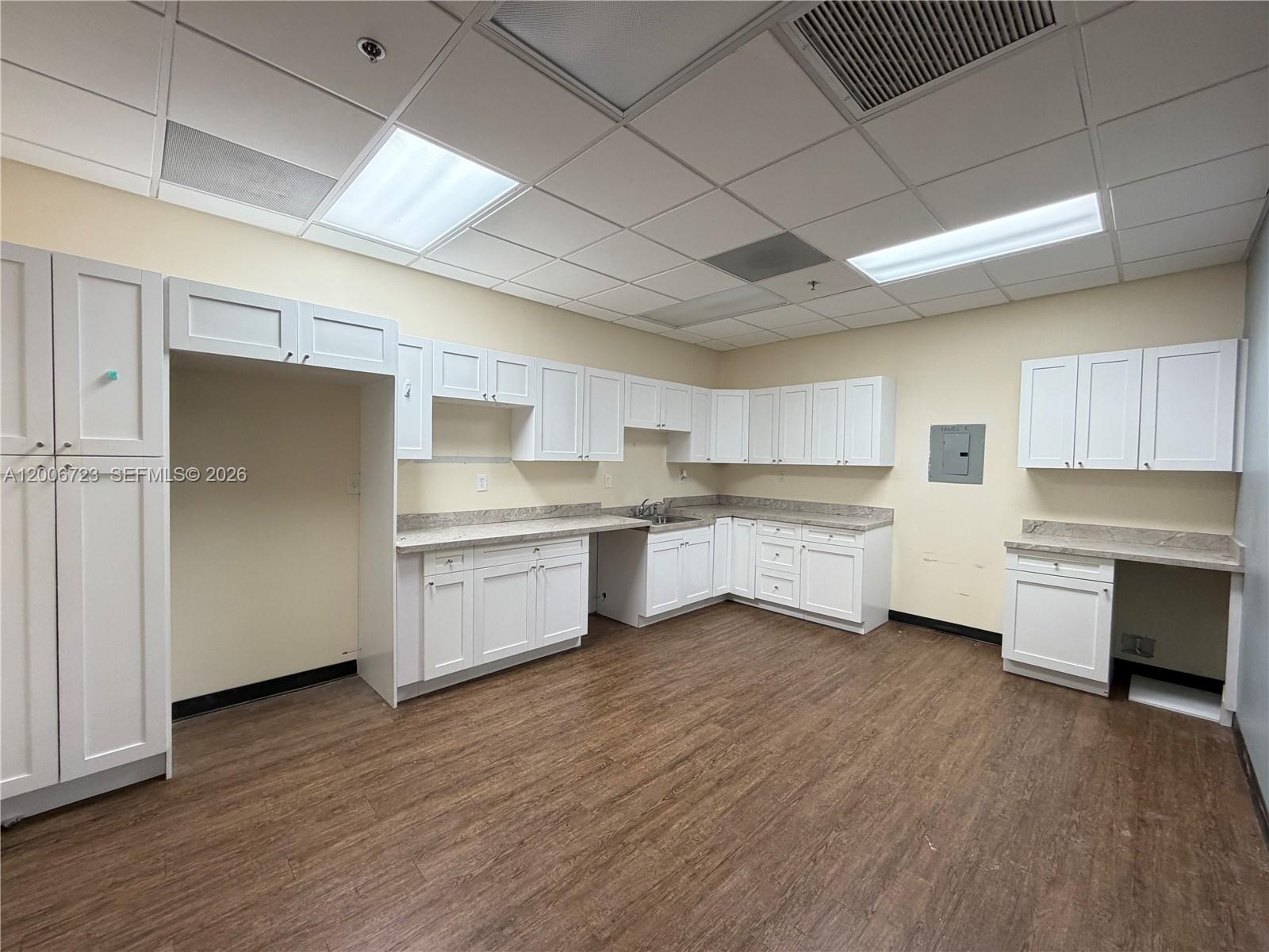 A commercial kitchen space features white cabinets, laminate countertops, and wood-look flooring — 4400 W Sample Rd # 250, Coconut Creek FL 33073, COCONUT CREEK, FL