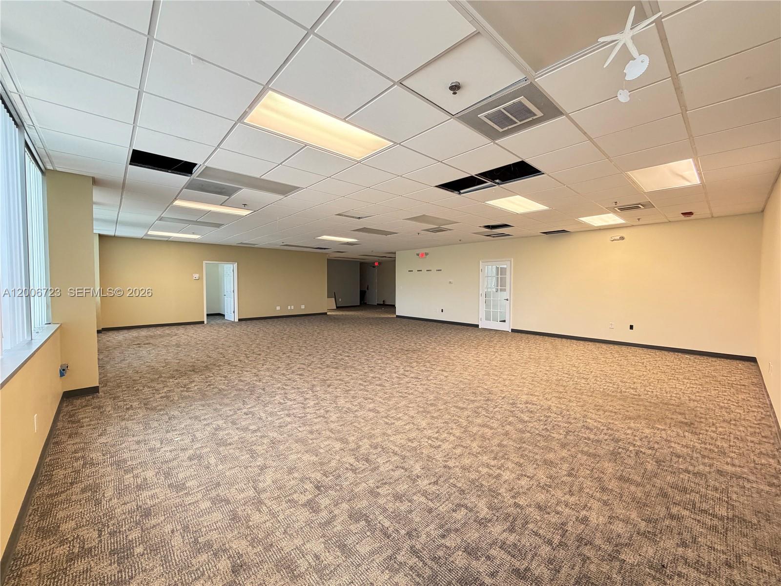 An empty office space features beige walls, patterned carpet, and a drop ceiling with missing tiles — 4400 W Sample Rd # 250, Coconut Creek FL 33073, COCONUT CREEK, FL