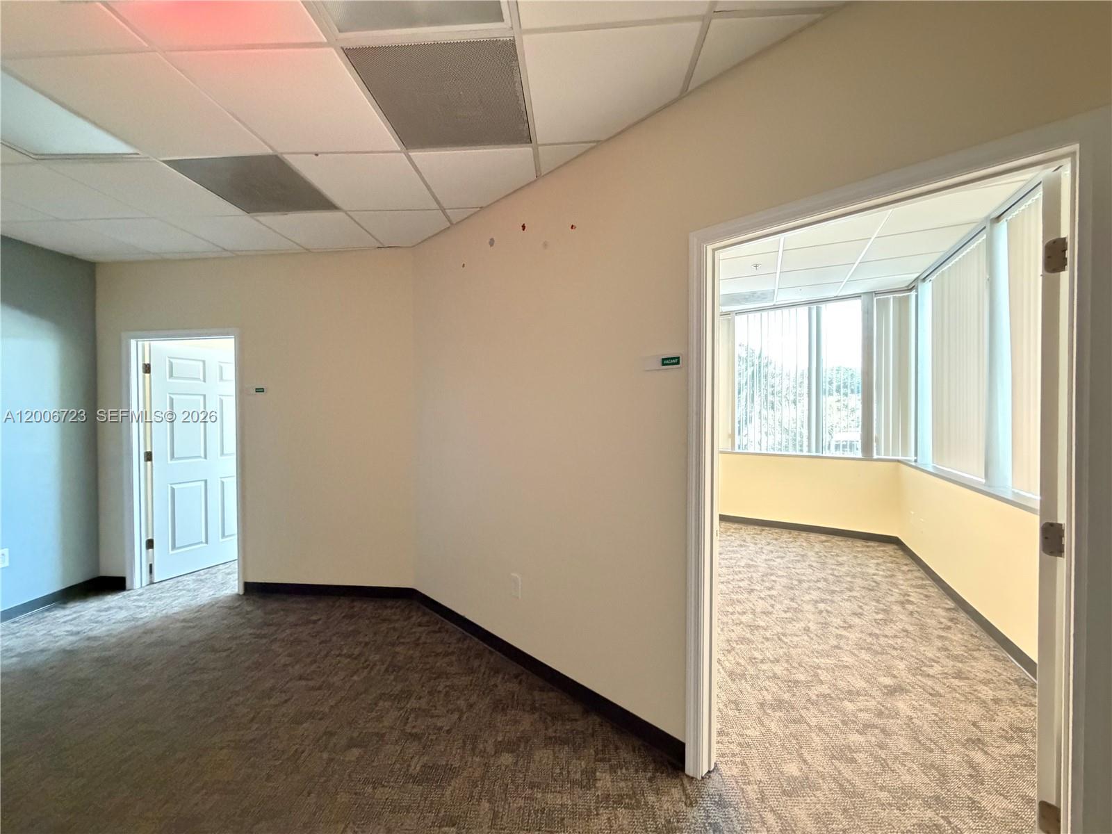 An office space features carpeted floors, a drop ceiling, and an open doorway to another room — 4400 W Sample Rd # 250, Coconut Creek FL 33073, COCONUT CREEK, FL
