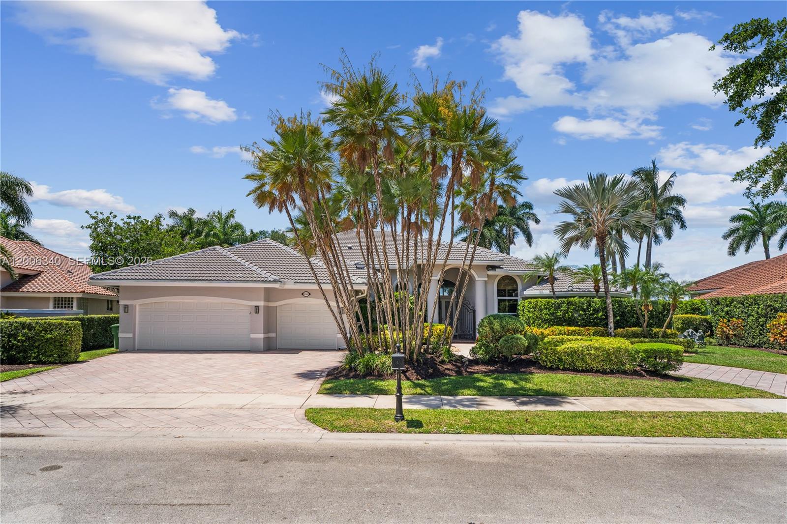 A single-story house with a tiled roof, a three-car garage, and palm trees in front — 2942 Medinah, Weston FL 33332, WESTON, FL