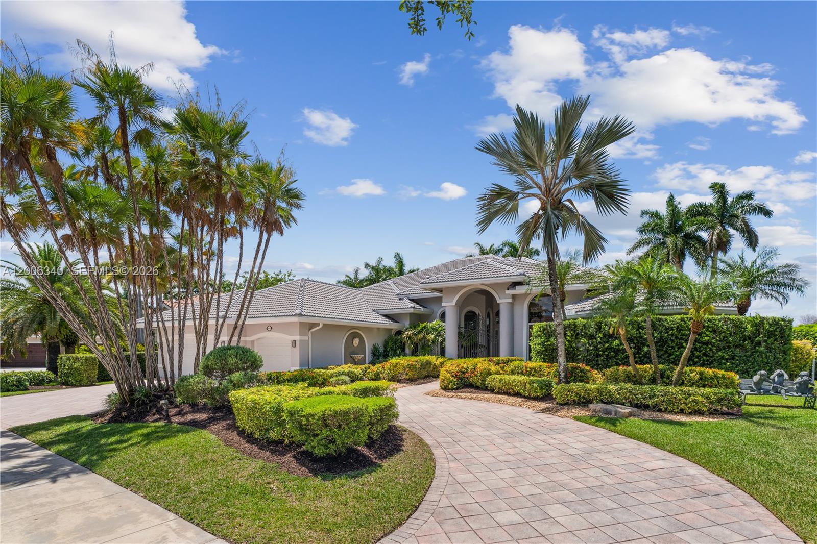 A single-story house with a tiled roof, arched entryway, and a paved driveway surrounded by landscaping — 2942 Medinah, Weston FL 33332, WESTON, FL