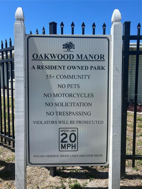 A sign for Oakwood Manor 55+ community stands in front of a black metal fence — 3221 SWEET GUM TERRACE, SARASOTA, FL