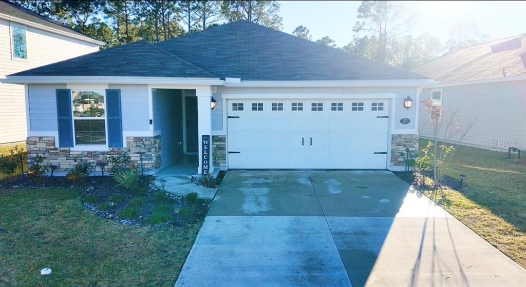 A single-story house with light blue siding, a stone facade, and a two-car garage — 37 WILLOW STREET, PALM COAST, FL