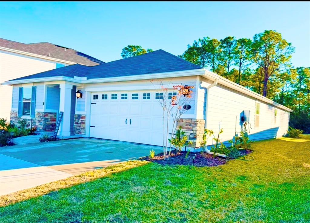 A single-story house with a white garage door, stone accents, and a blue-trimmed window — 37 WILLOW STREET, PALM COAST, FL