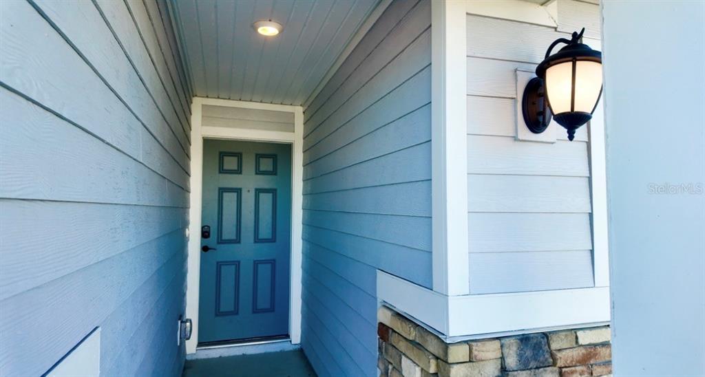A blue front door is set within a covered entryway with light blue siding — 37 WILLOW STREET, PALM COAST, FL