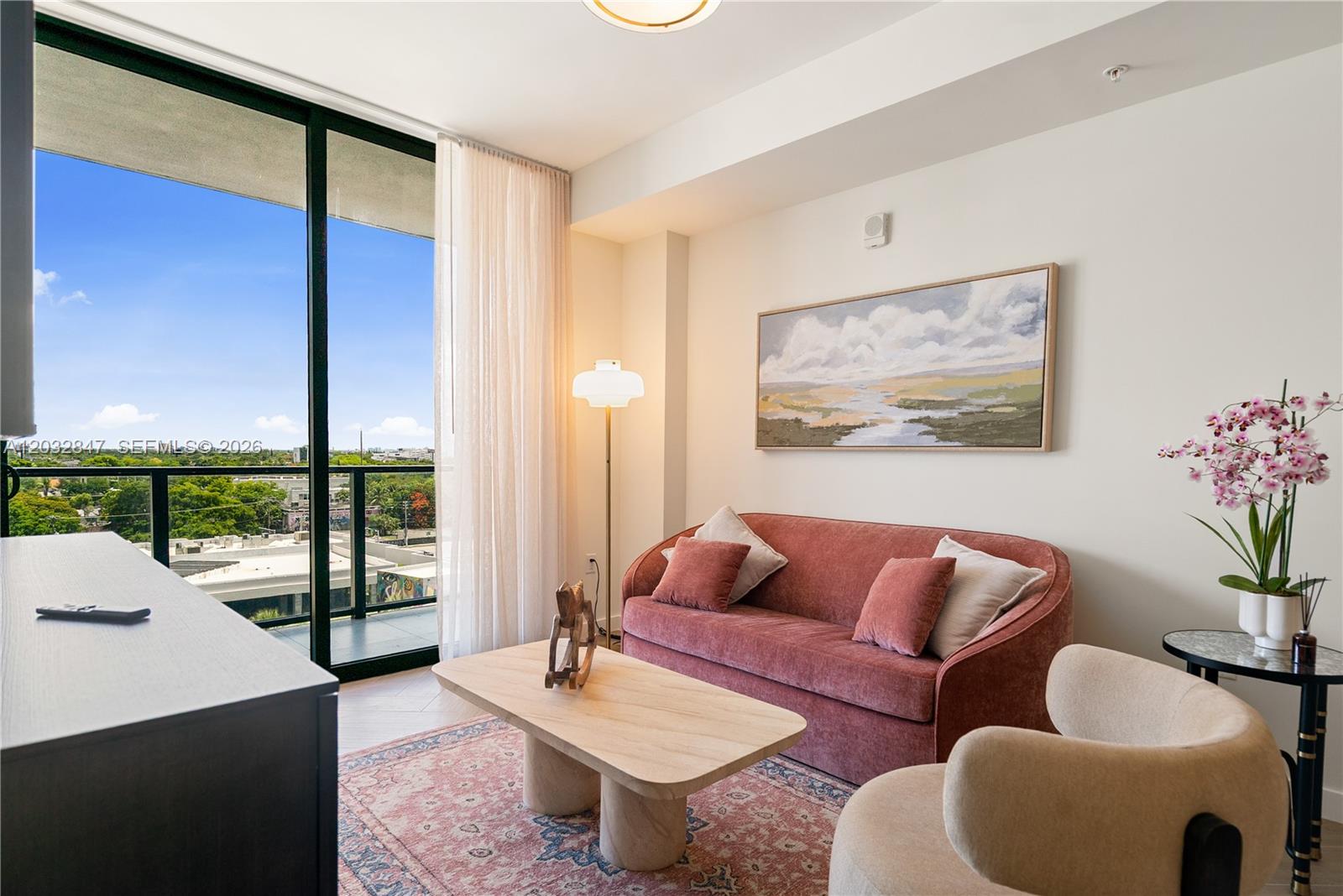 A living room features a pink sofa, a wooden coffee table, and a balcony view — 2700 NW 2ND AVE # 728, Miami FL 33127, MIAMI, FL