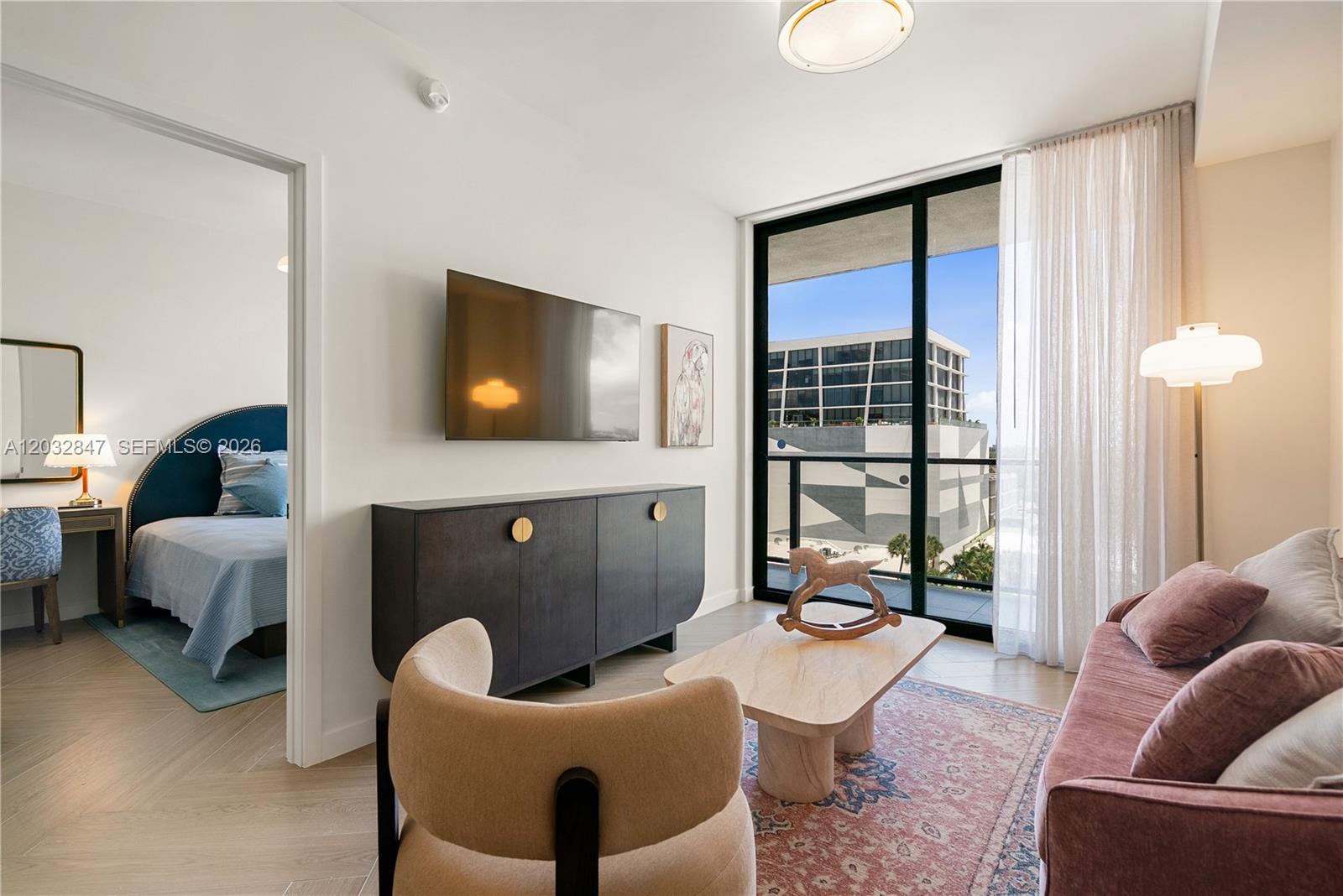 A living room features a dark cabinet, a pink sofa, and a view of buildings — 2700 NW 2ND AVE # 728, Miami FL 33127, MIAMI, FL