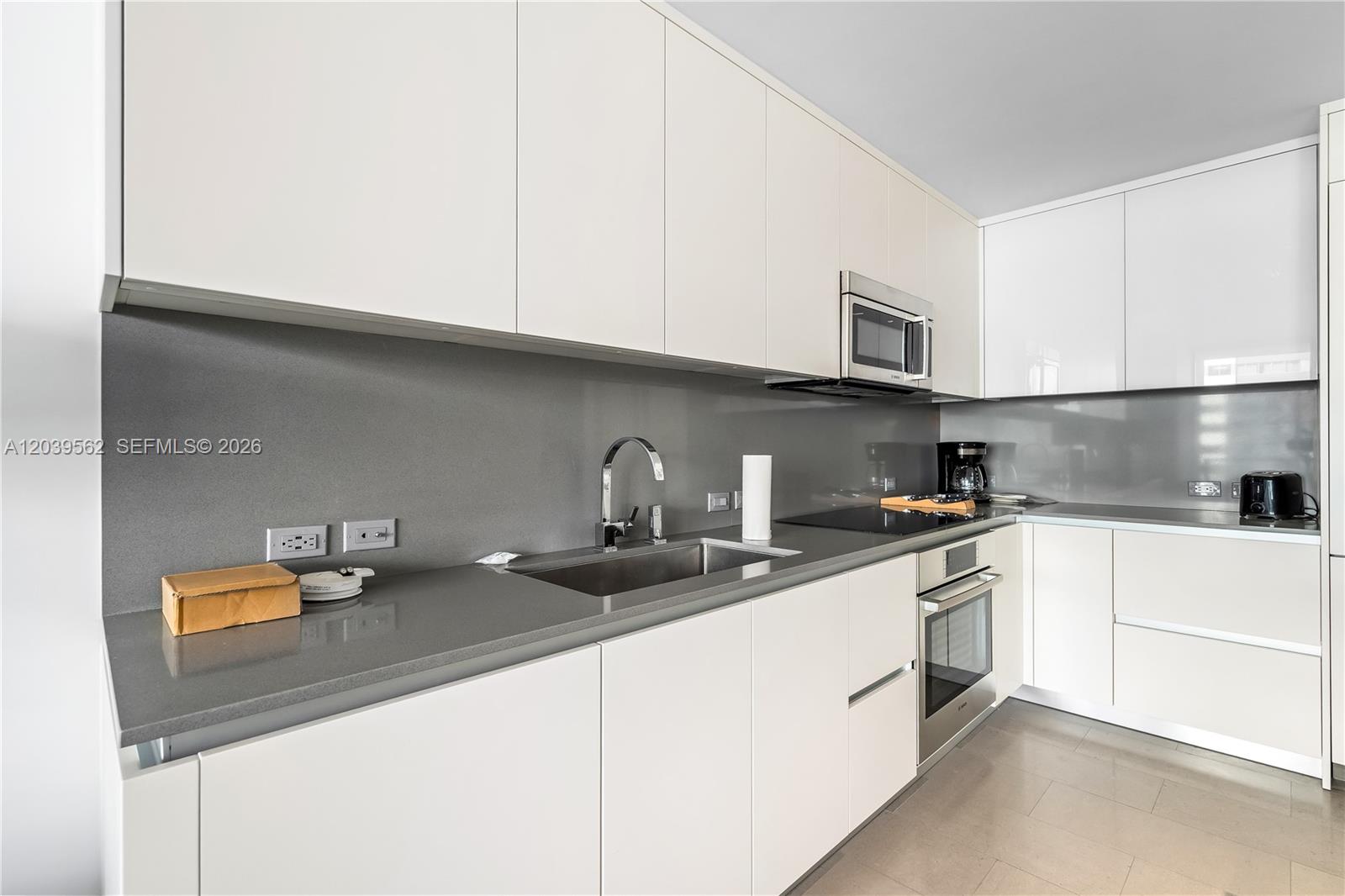 A modern kitchen features white flat-panel cabinets, gray countertops, and a gray backsplash — 88 SW 7th St # 1006, Miami FL 33130, MIAMI, FL