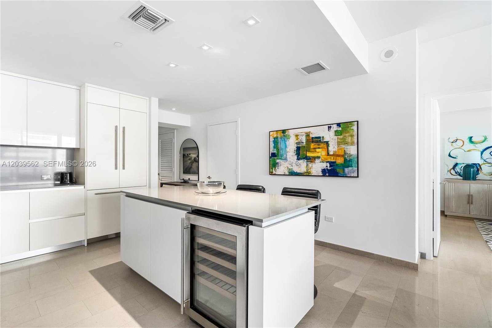A modern kitchen features white cabinetry, a central island with a wine cooler, and tile flooring — 88 SW 7th St # 1006, Miami FL 33130, MIAMI, FL
