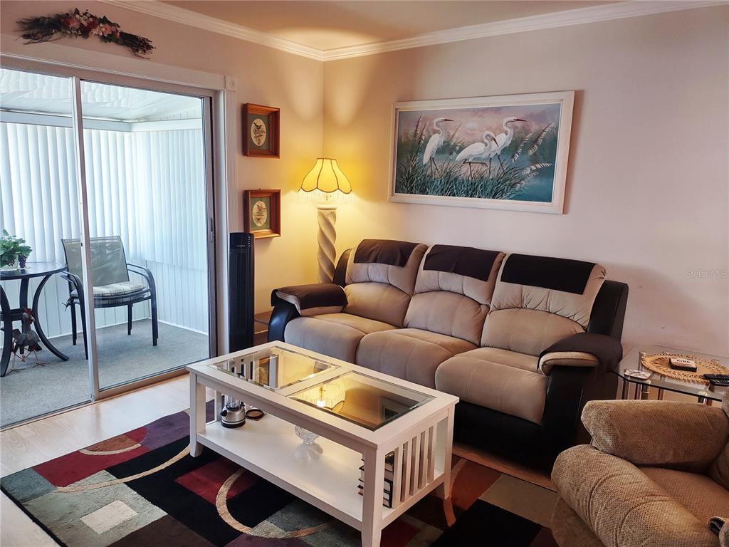 A living room features a beige and brown sofa, a white coffee table, and a lamp — 1815 SUNNY DRIVE UNIT E21, BRADENTON, FL