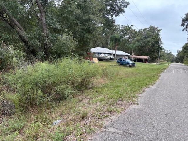 A view of a grassy lot with a house, a boat, and a car — FISHER LANE COURT, OCKLAWAHA, FL