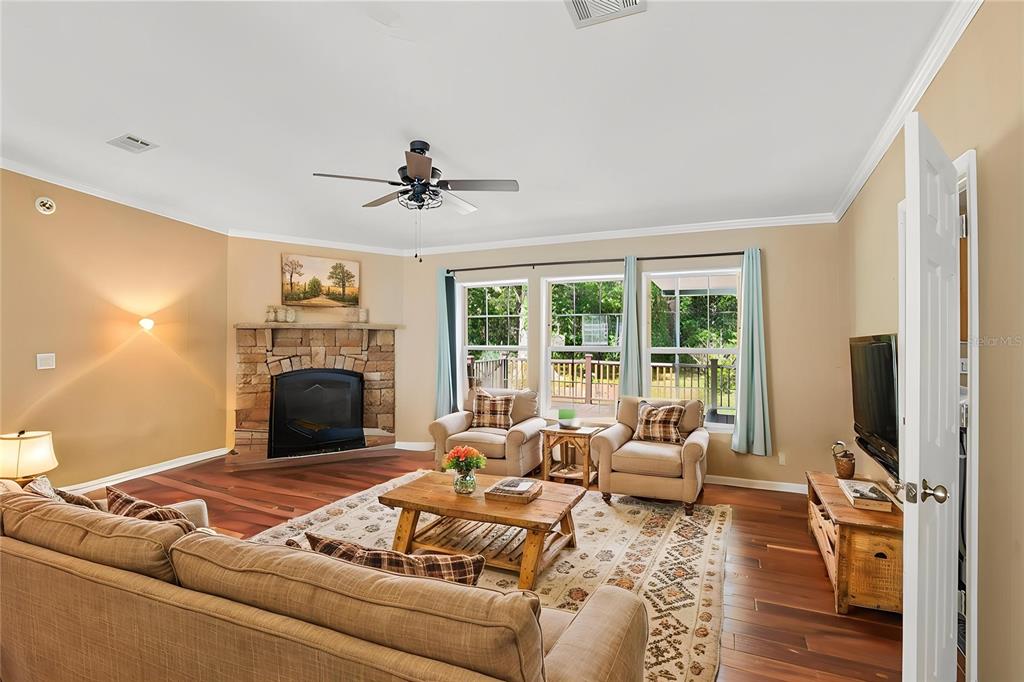 A living room features a stone fireplace, hardwood floors, and a view of a deck — 6221 EMERSON ROAD, BROOKSVILLE, FL