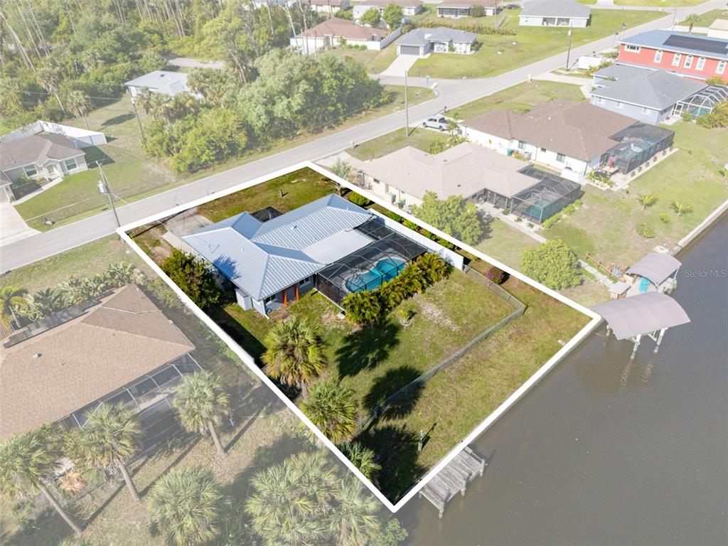 An aerial view shows a house with a pool and dock on a waterfront lot — 2440 AUBURN BOULEVARD, PORT CHARLOTTE, FL