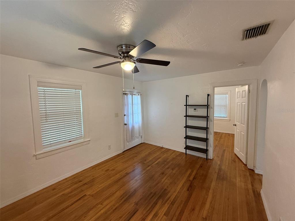 A room with hardwood floors, a ceiling fan, a window with blinds, and a doorway — 5521 5TH AVENUE N, ST PETERSBURG, FL