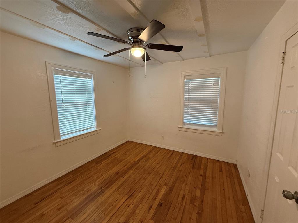 An empty bedroom features hardwood floors, two windows with blinds, and a ceiling fan — 5521 5TH AVENUE N, ST PETERSBURG, FL