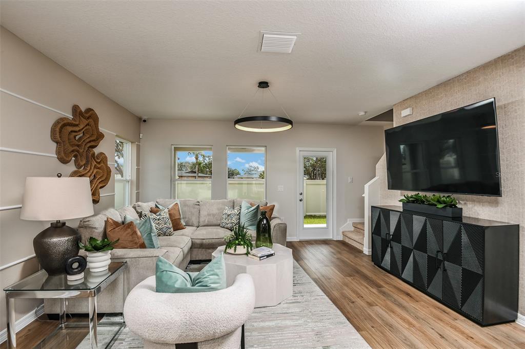 A living room features a sectional sofa, a television, and a modern circular light fixture — 9864 PELICAN COAST DRIVE, DADE CITY, FL