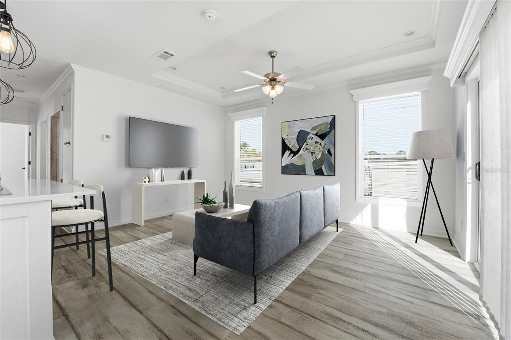 This living room features a gray sofa, a wall-mounted television, and light wood-look flooring — 3710 GULF OF MEXICO DRIVE UNIT F2, LONGBOAT KEY, FL