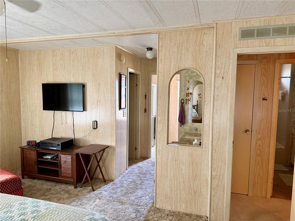 A living room features wood-paneled walls, carpeted floors, a ceiling fan, and several armchairs — 6571 NE 1ST PLACE, OCALA, FL