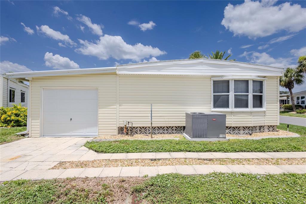 A light yellow manufactured home with a white garage door and an exterior AC unit — 2100 KINGS HIGHWAY UNIT 683, PORT CHARLOTTE, FL